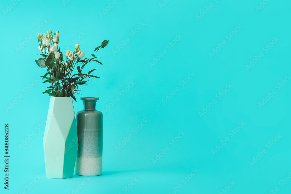 Vases with bouquet of flowers on color background