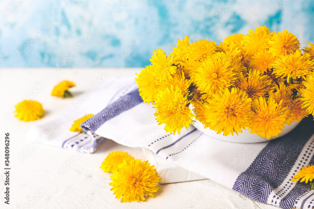 Bowl with beautiful dandelions on table