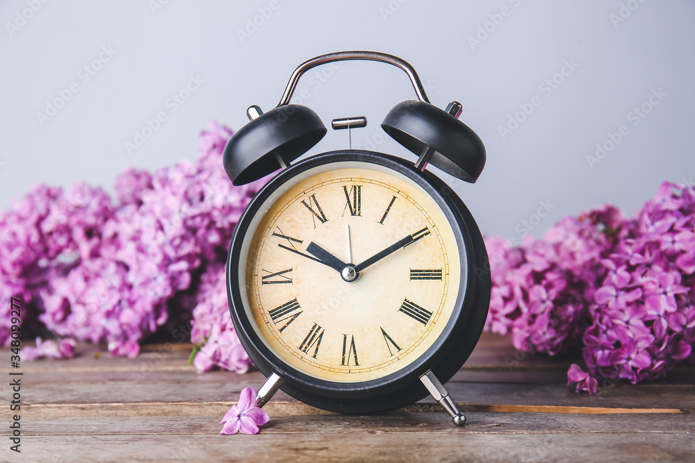 Alarm clock and flowers on table. Spring time