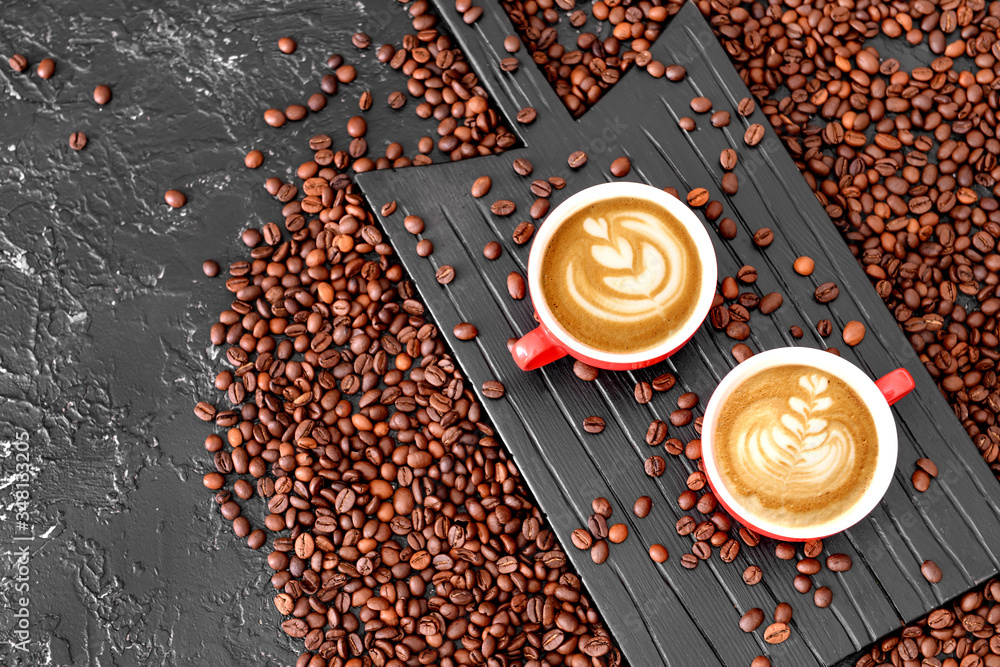 Cups of hot coffee and beans on table