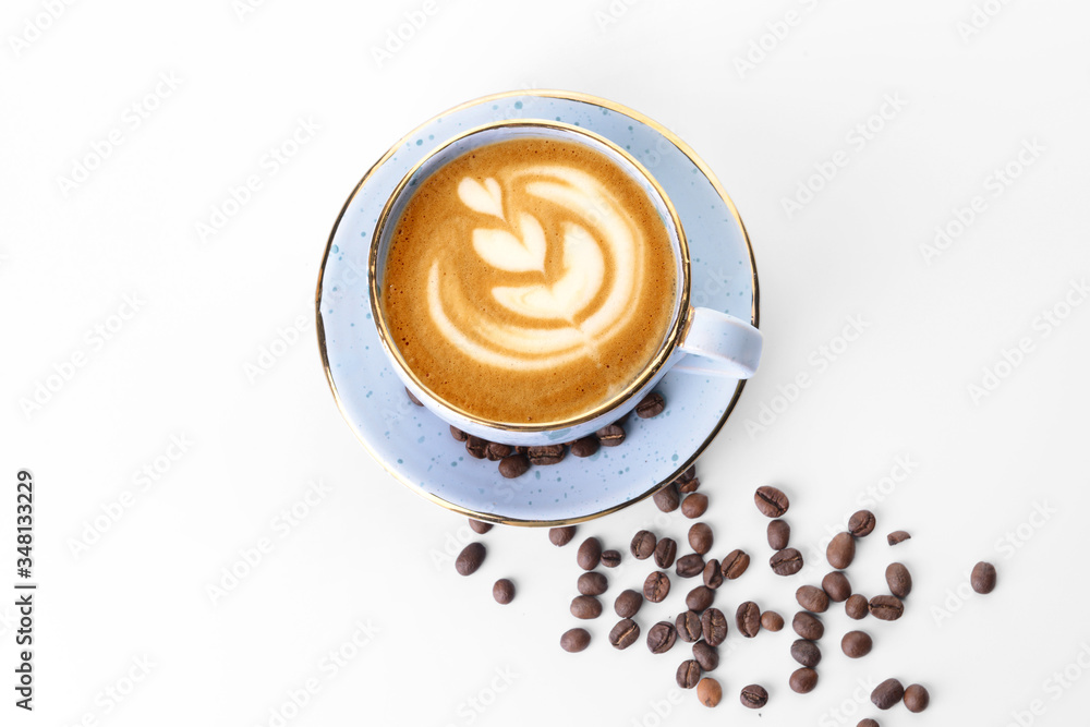 Cup of tasty cappuccino and coffee beans on white background