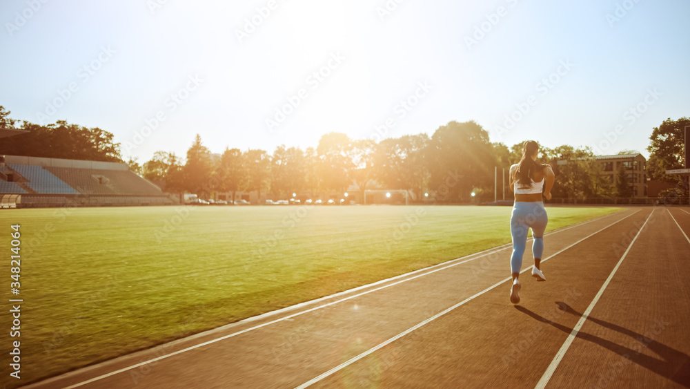 Beautiful Fitness Girl in Light Blue Athletic Top and Leggings Jogging in the Stadium. She is Runnin