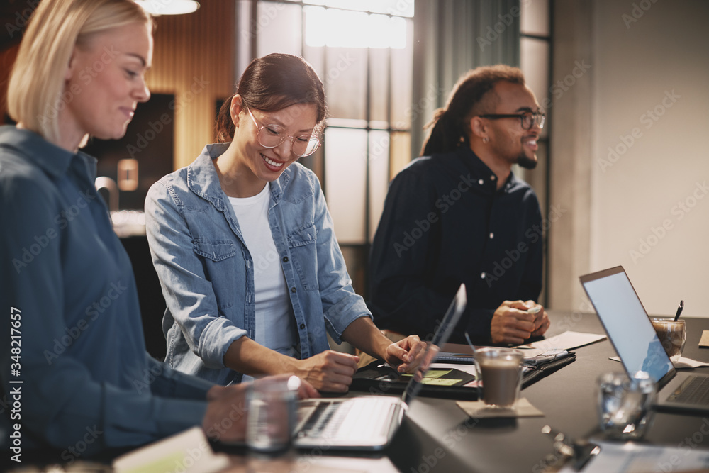 Diverse businesspeople smiling and talking together in an office