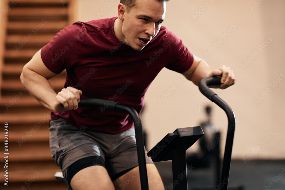 Young man riding a stationary bike in a gym