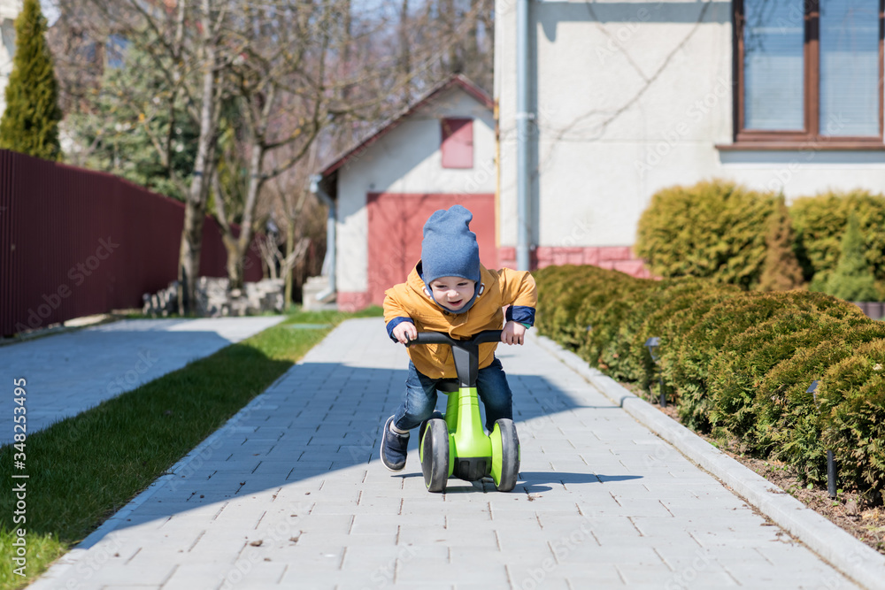 Little boy on his bike on paving path near his house. Happy childhood concept