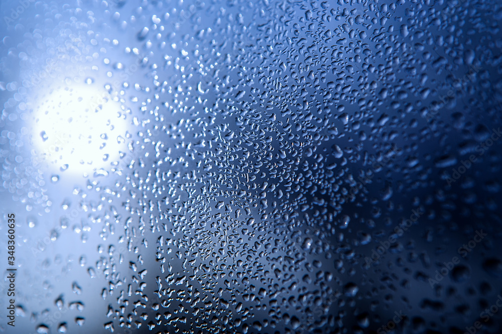 patterns on glass, frosty drawings in winter on a window, blue background and ice drawings, droplets