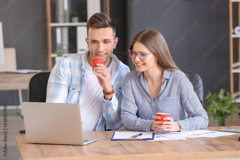 Young colleagues drinking coffee while working in office