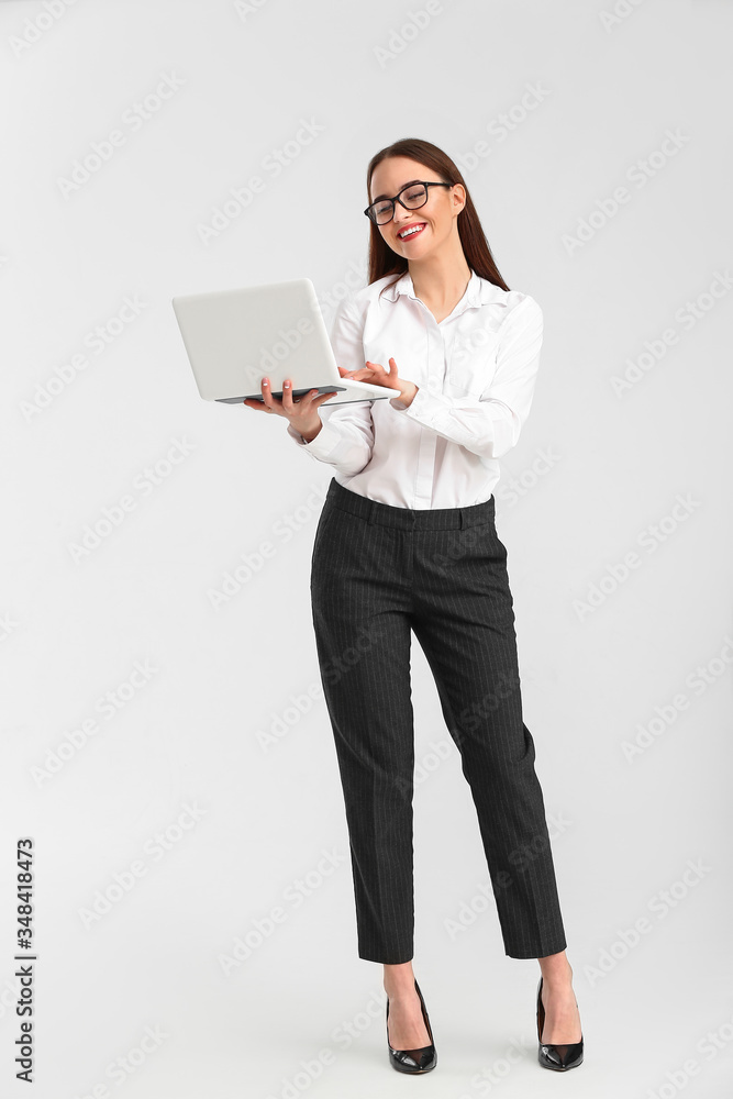 Beautiful young secretary with laptop on white background