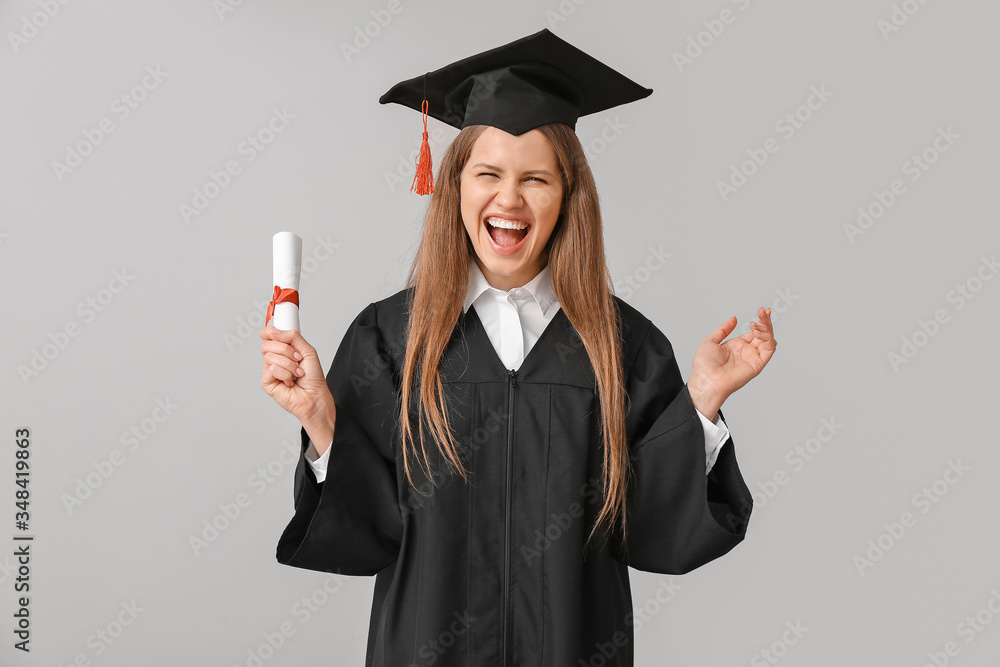 Happy female graduating student with diploma on light background