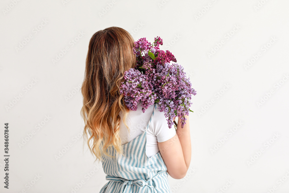 Beautiful young woman with bouquet of lilac flowers on white background