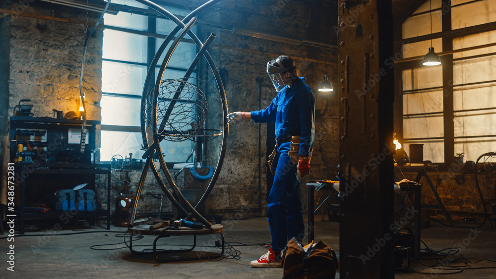 Young Contemporary Female Artist in Blue Jumpsuit and Safety Mask is Fitting a Metal Ring to a Tube 