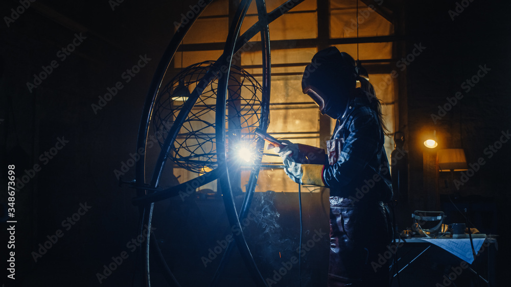 Young Contemporary Female Artist is Welding Her Metal Tube Sculpture with a Handheld Power Tool in a