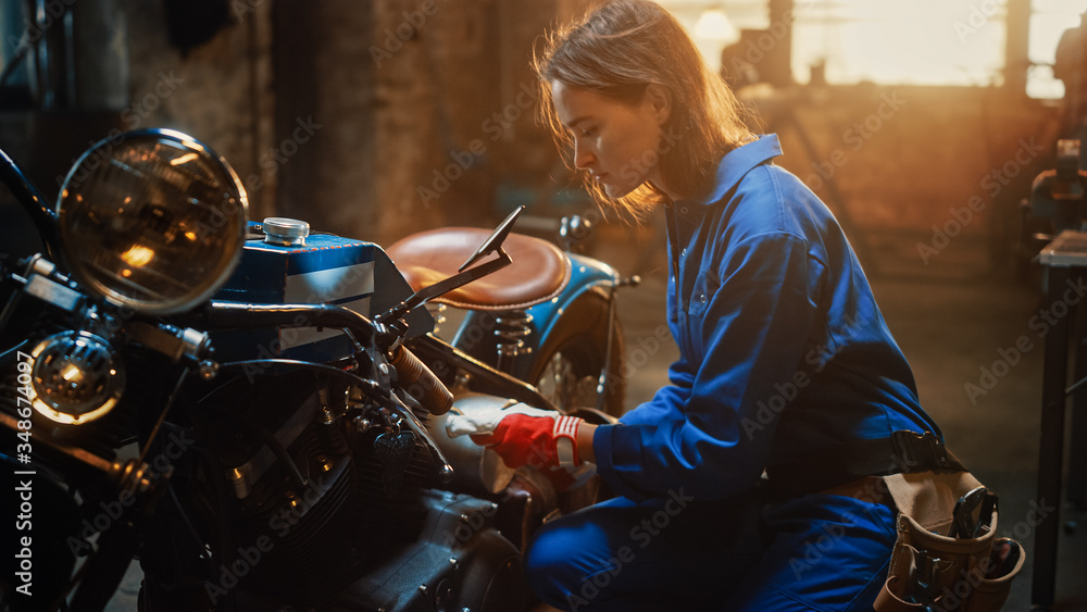 Young Beautiful Female Mechanic is Working on a Custom Bobber Motorcycle. Talented Girl Wearing a Bl