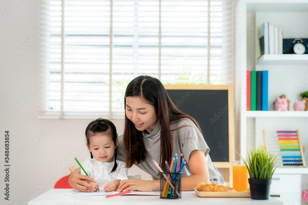 Asian kindergarten student girl with mother painting picture in book with color pencil at home, Home