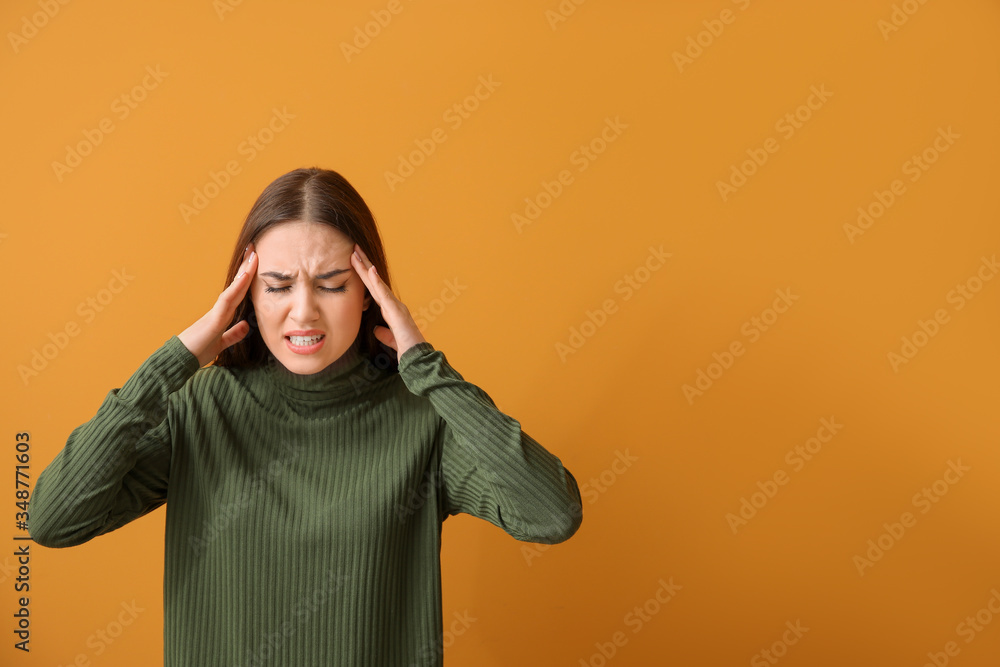 Young woman suffering from loud noise on color background