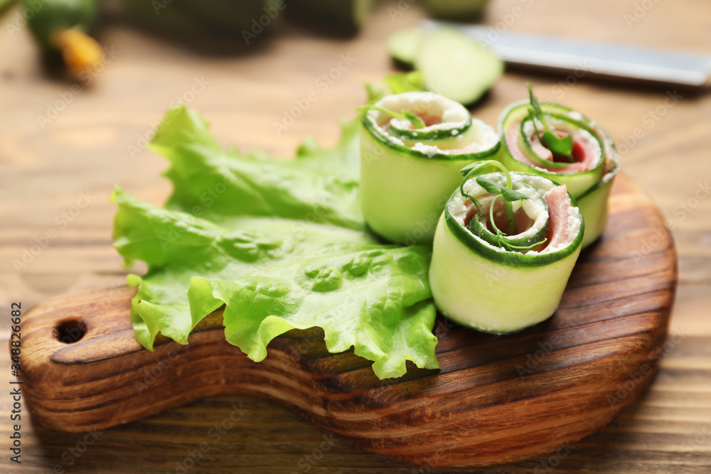 Board with tasty cucumber rolls on table