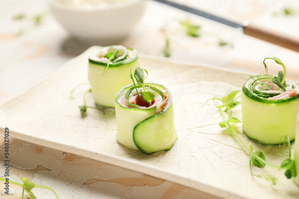 Plate with tasty cucumber rolls on table