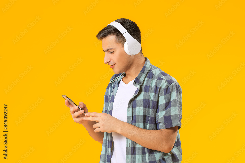 Portrait of young man listening to music on color background