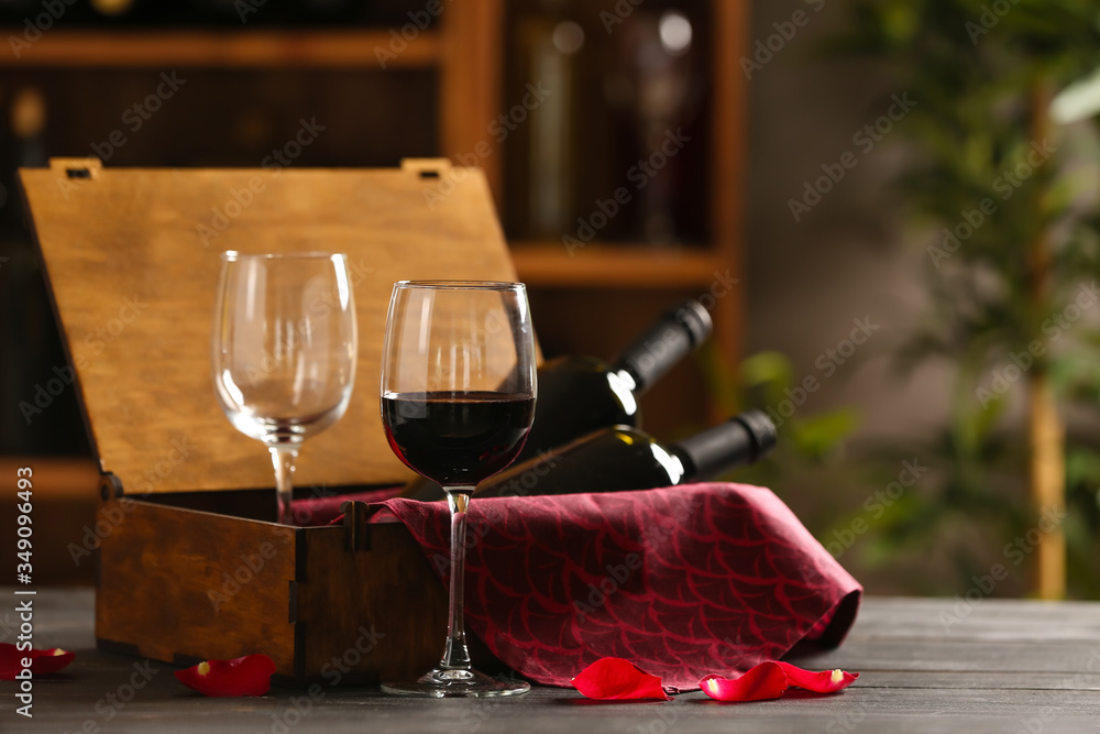 Box with bottles of wine and glasses on table