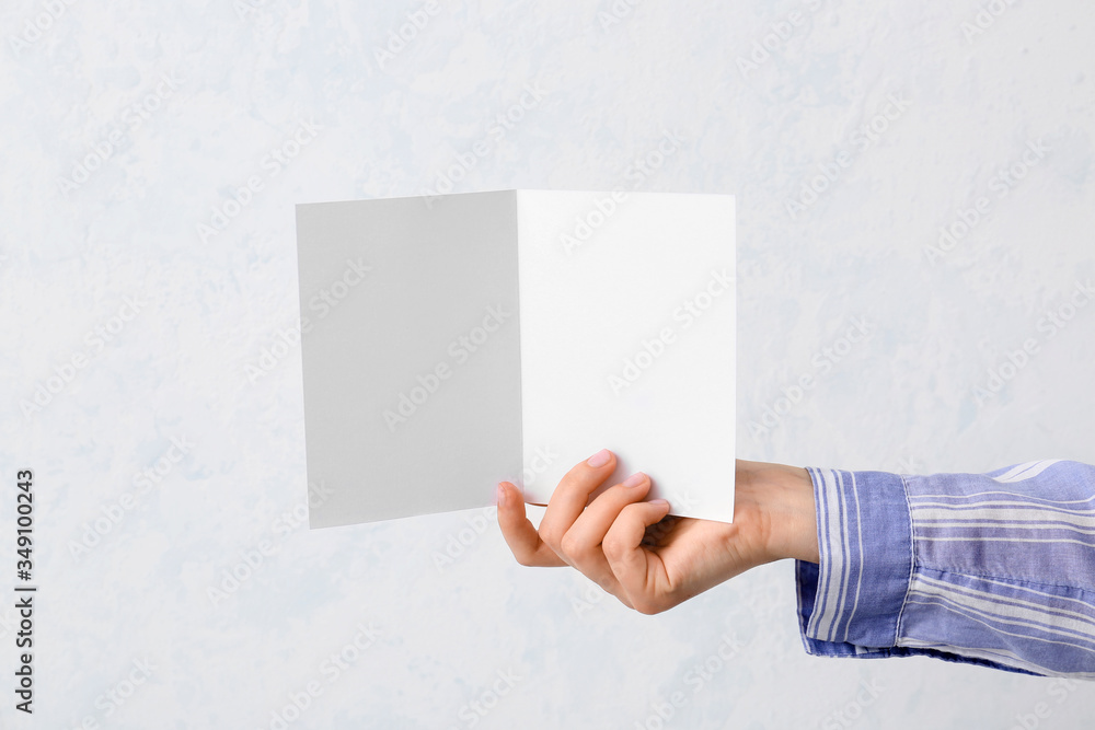 Female hand with blank card on light background