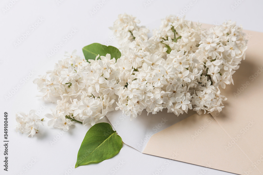 Beautiful lilac flowers and envelope on white background