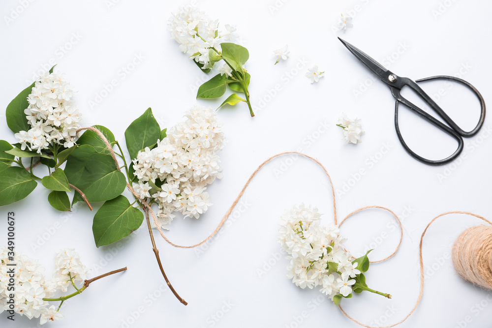 Beautiful lilac flowers, thread and scissors on white background