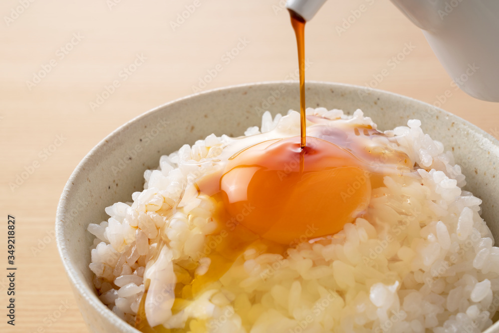 pouring soy sauce over rice with an egg