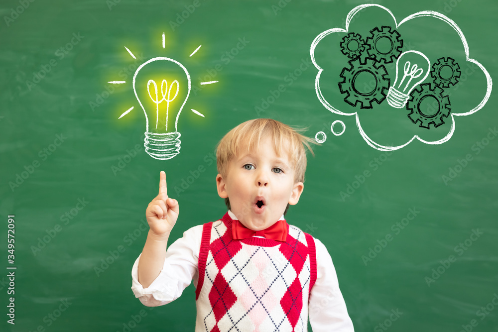 Bright idea! Happy child student against green chalkboard