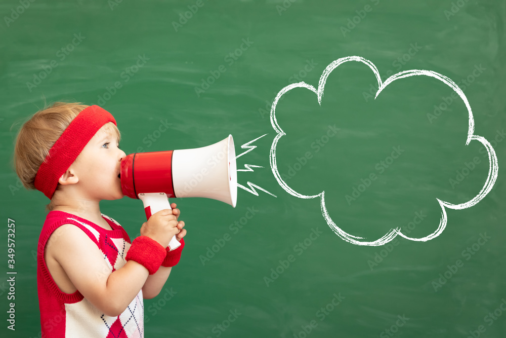 Happy child student speaking by megaphone in class