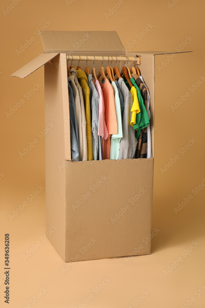 Moving box with clothes on color background