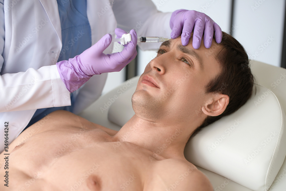 Handsome man receiving filler injection in beauty salon