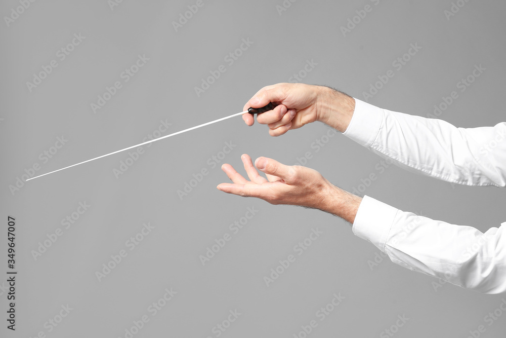 Hands of senior male conductor on grey background