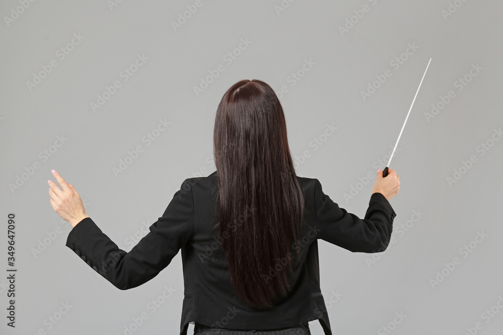 Young female conductor on grey background