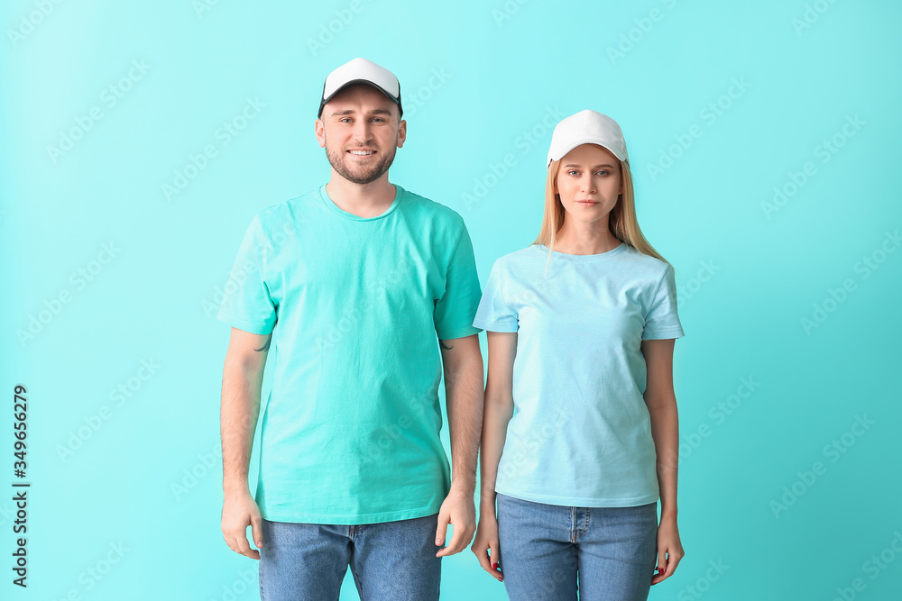 Young couple in stylish caps on color background