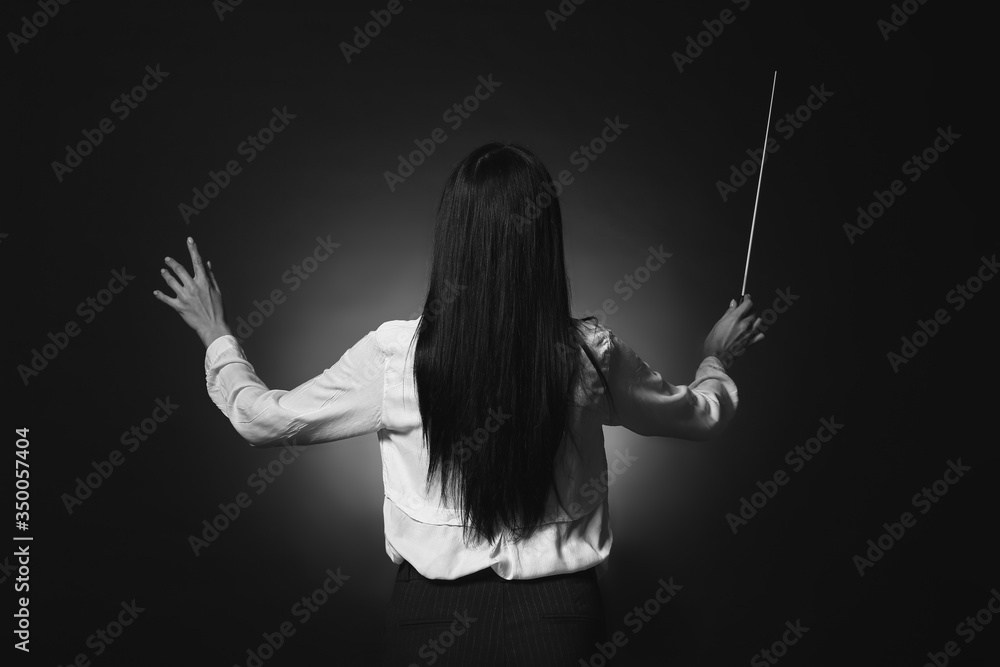 Black and white photo of young female conductor on dark background