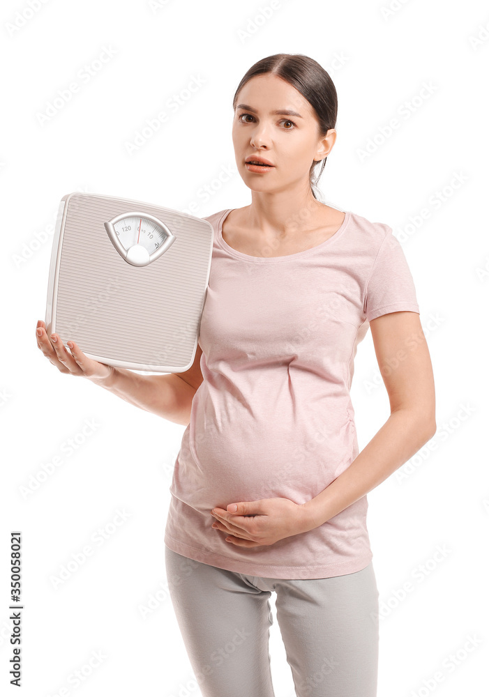 Young pregnant woman with measuring scales on white background