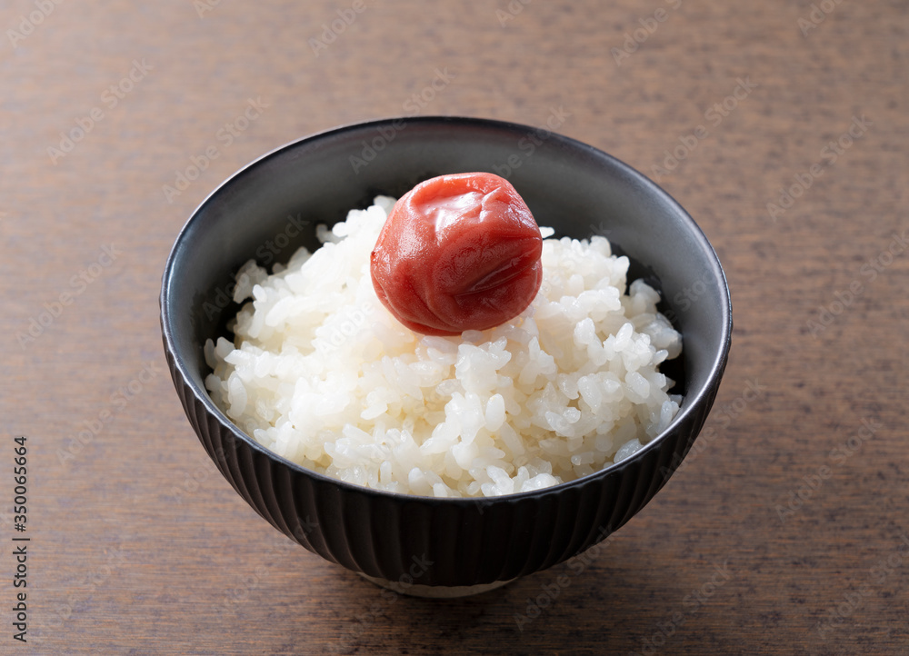 木制背景下的日本腌李子和新鲜煮熟的米饭