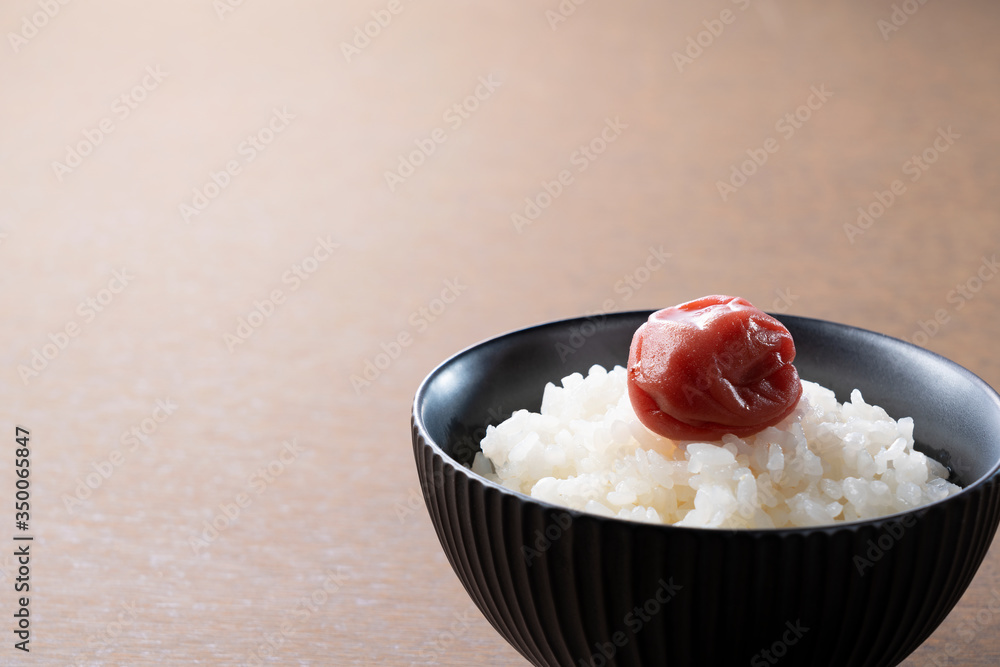 木制背景下的日本腌李子和新鲜煮熟的米饭