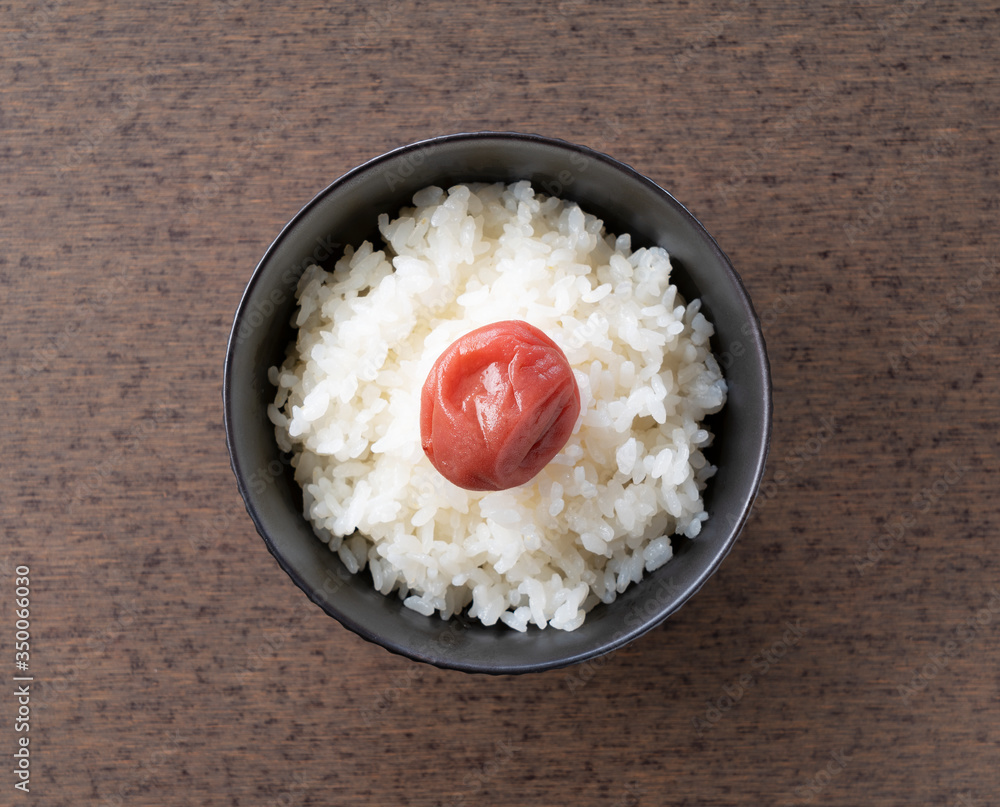 木制背景下的日本腌李子和新鲜煮熟的米饭