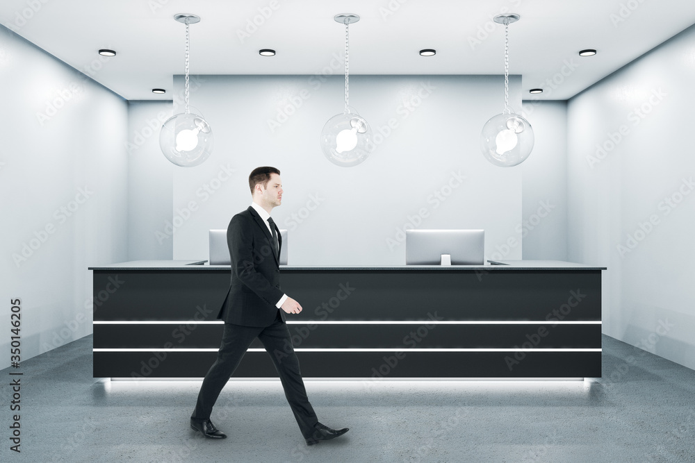 Businessman walking in reception room with two computers.