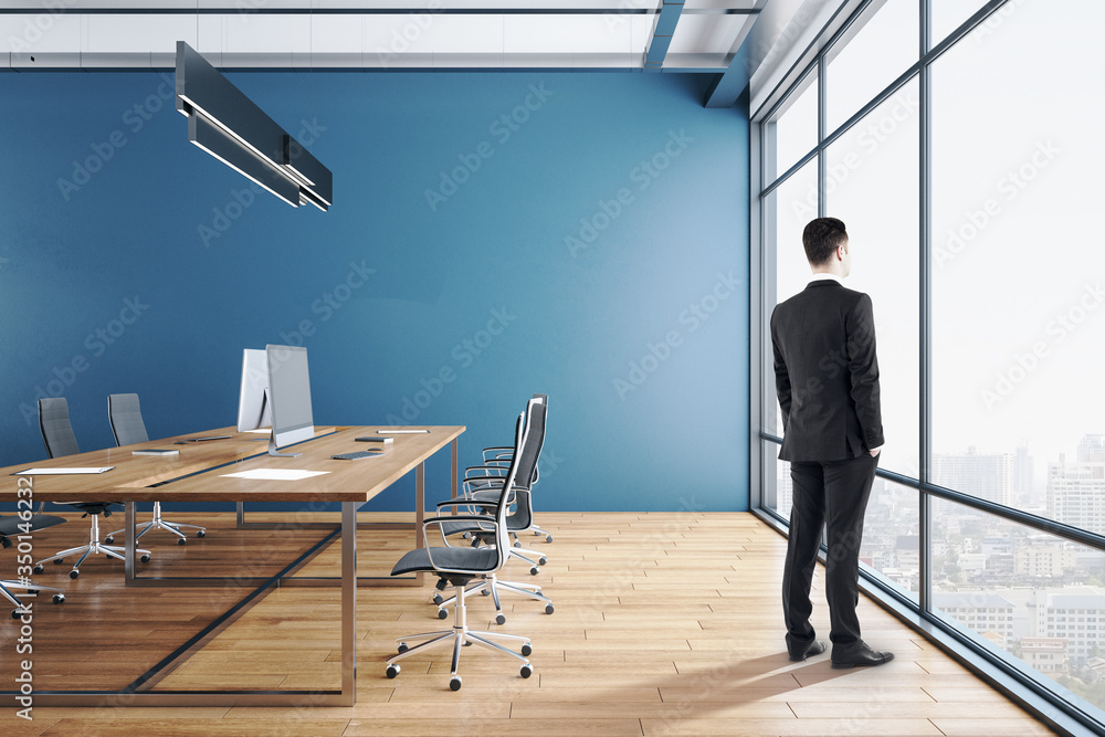 Businessman standing in coworking office interior with city view.