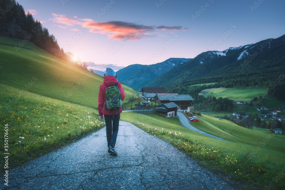 美丽的年轻女子背着背包站在秋天日落的山路上。风景