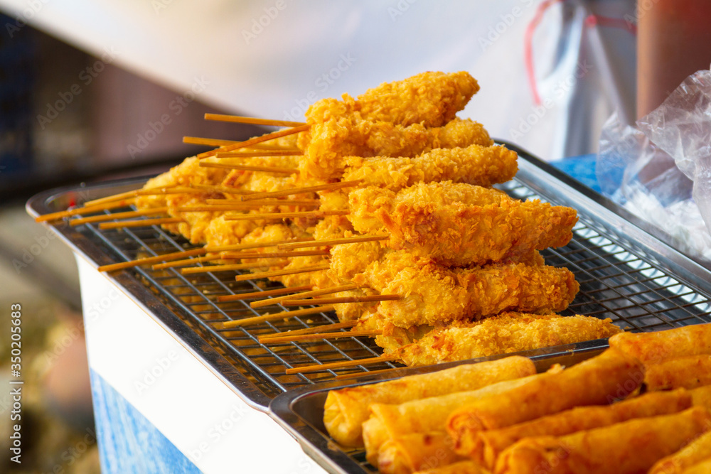 Roasted chicken on a stick as street food at a market in Thailand