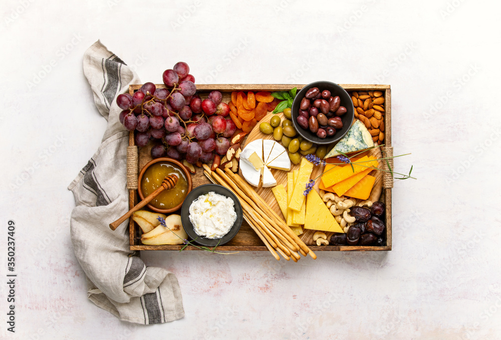 Cheese board with grapes, nuts and dried fruits, overhead view