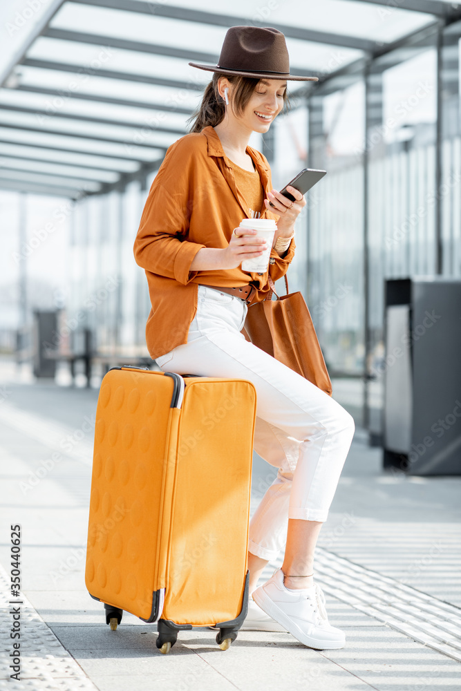 Young female traveler with a luggage at the transport stop