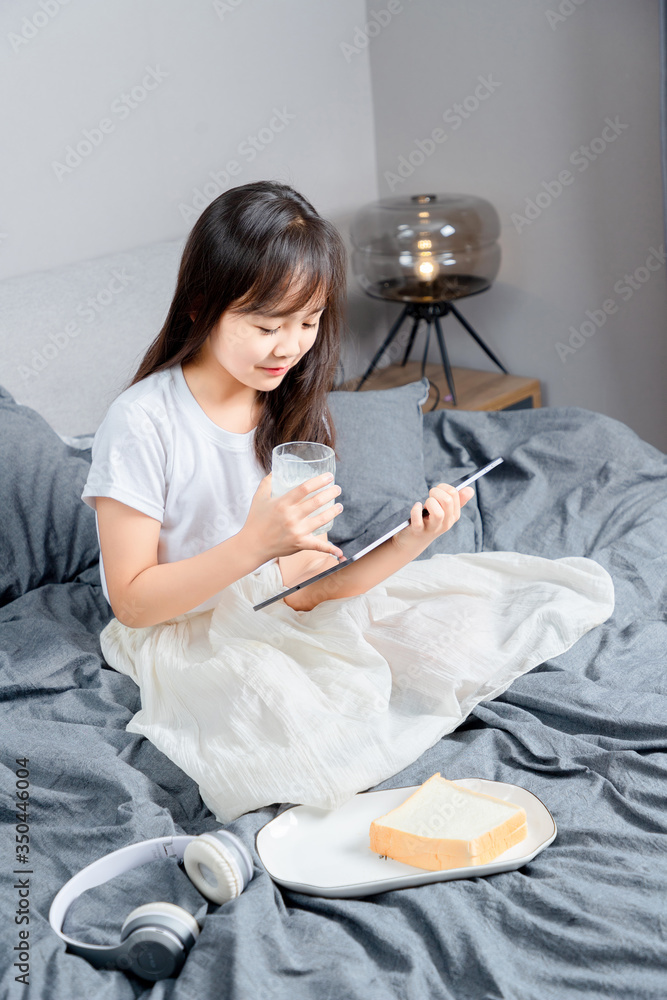 Asian little girl sitting in bed eating breakfast