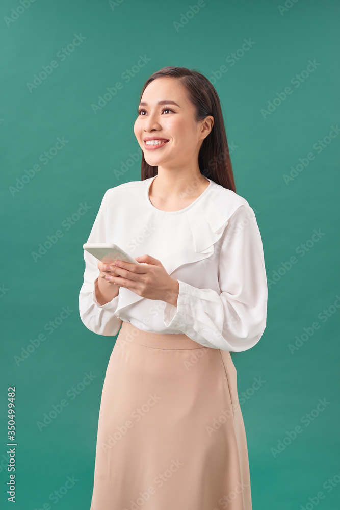 Cheerful cute beautiful young woman chatting by mobile phone isolated over turquoise  background. Lo