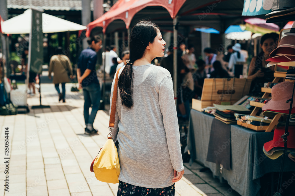 美丽的亚洲韩国年轻女孩走在街上的背影。迷人的女士背着黄色的袋子