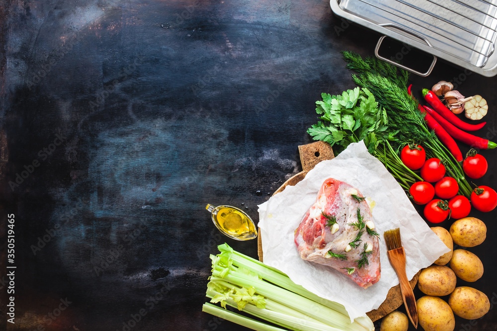 Raw turkey thigh on a wooden board with vegetables and baking on a dark metal table, top view. Ingre