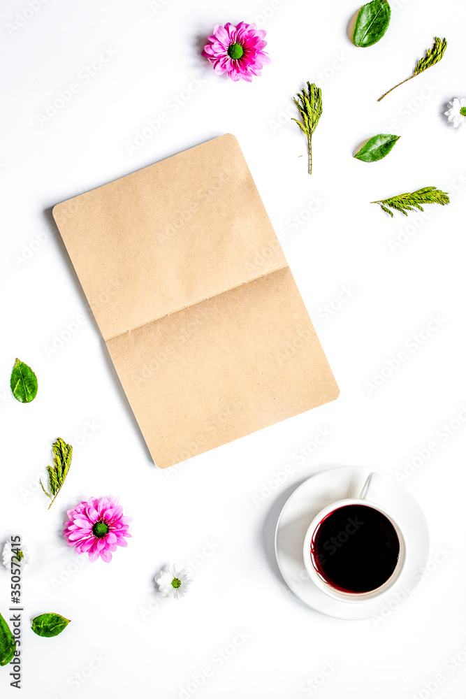 Coffee cup with flower petals and notebook top view mock-up